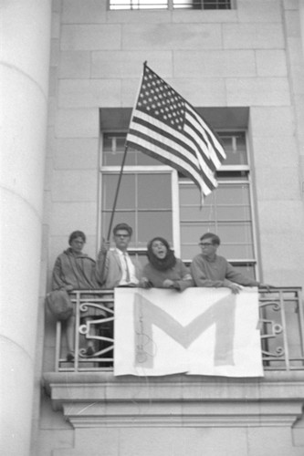Students on Sproul Hall balcony with flag
