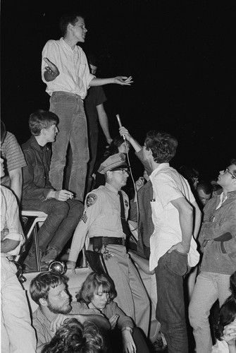 Sid Stapleton speaking from top of police car during evening