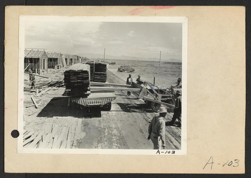 Poston, Ariz.--Site No. 1. Unloading lumber with bulldozer in the construction of barracks for evacuees of Japanese ancestry who will spend the duration in War Relocation Authority centers. Photographer: Clark, Fred Poston, Arizona