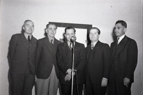 Five men standing in front of a microphone