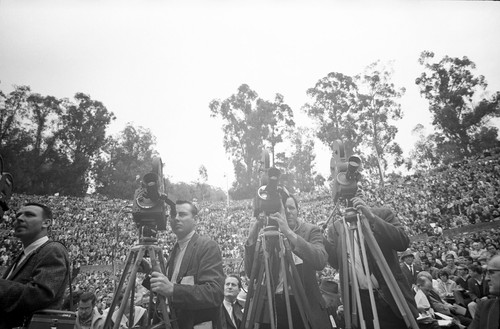 Newsmen and photographers at the Greek Theater with audience in the background