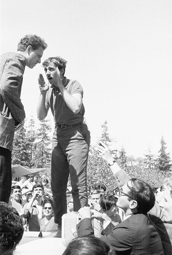 Jack Weinberg and Mario Savio speaking to each other on top of police car