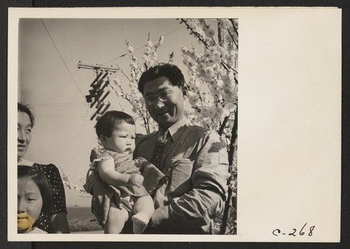 Henry Mitarai, 36-year-old successful large-scale farm operator, holding the youngest of his four daughters prior to evacuation. These residents of Japanese ancestry will spend the duration at War Relocation Authority Centers. Photographer: Lange, Dorothea Mountain View, California